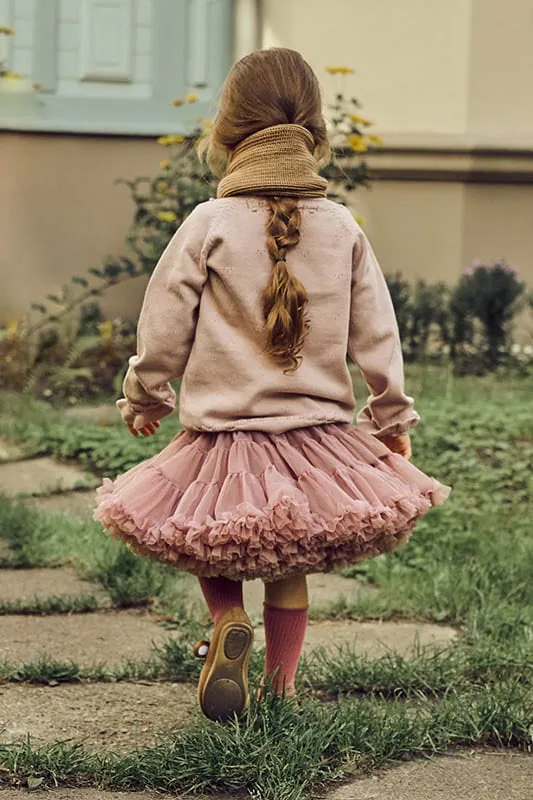 Niña jugando en Sopot con jersey rosa y falda de tul rosa