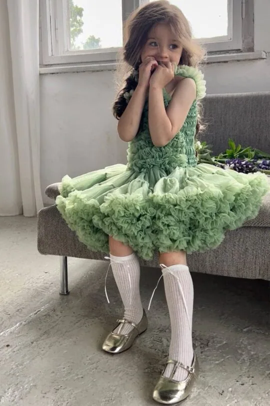 Niña con vestido de tul verde y medias blancas hasta la rodilla y bailarinas