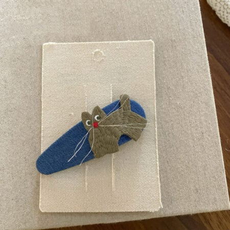 Haarnadel für ein Mädchen in Blau mit einer gestickten Katze in Oliv-Grau-Tönen.
