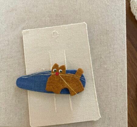 Haarnadel mit gestickter brauner Katze auf blauem Hintergrund, für ein Mädchen.
