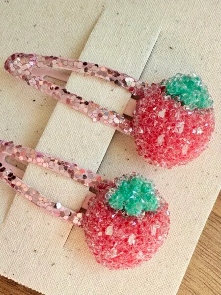 Hair clips for girls in the shape of strawberries, in pink with green accents.
