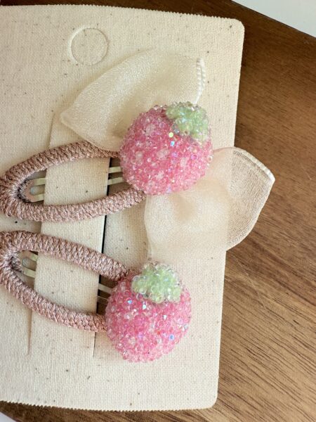 Haargummis für Mädchen in Rosa mit einer erdbeerförmigen Verzierung und einer kleinen Schleife.