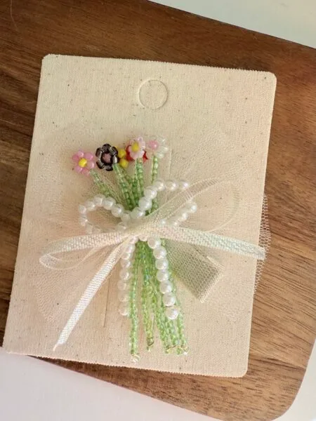 Dekorative Haarspange für Mädchen mit blumenförmigen Perlen in Rosa-, Schwarz- und Grüntönen.