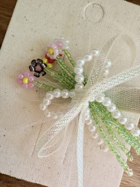Spilla con perline floreali nei toni del rosa, del verde e del bianco, decorata con accenti di perle.