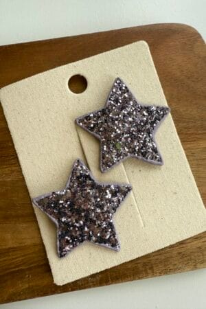 Brocade hair clips for a girl in the shape of stars in lilac color with glittering elements.