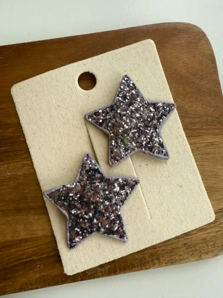 Brocade hair clips for a girl in the shape of stars in lilac color with glittering elements.