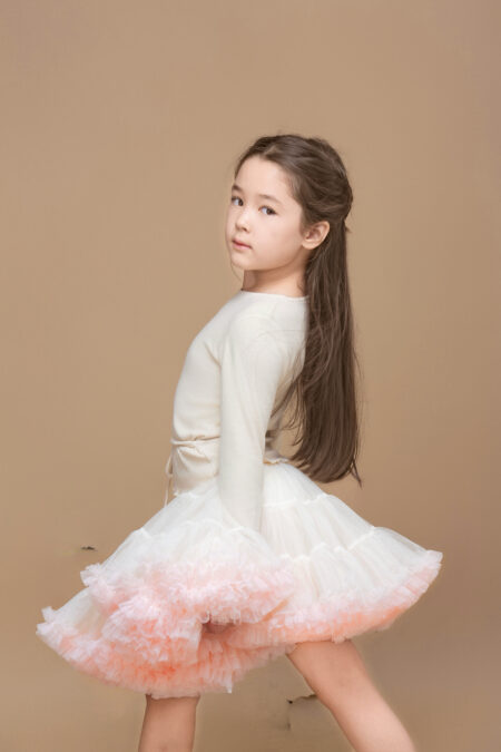 Dress for a girl in shades of white and pastel pink, with layered tulle and long sleeves.